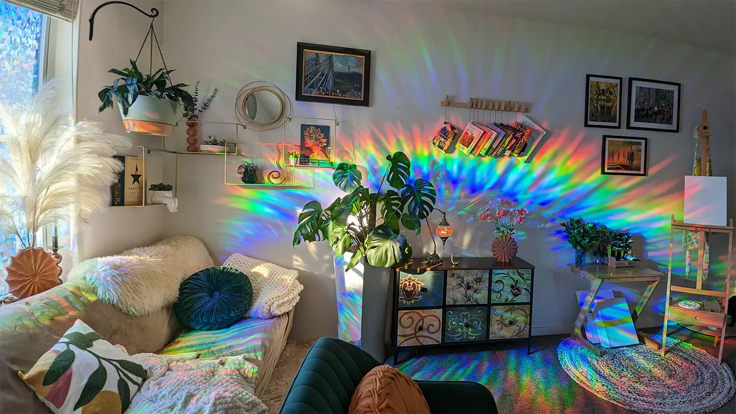 an office full of plants and feminine decor, a window casting a vivid rainbow across the wall
